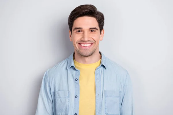 Фото довольно милого очаровательного молодого парня носить джинсовую рубашку улыбаясь изолированный серый цвет фона — стоковое фото