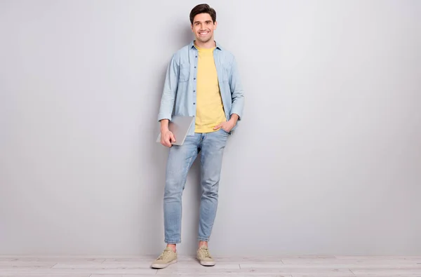 Photo of sweet attractive guy dressed denim shirt holding modern device empty space isolated concrete grey wall background — Stock Photo, Image