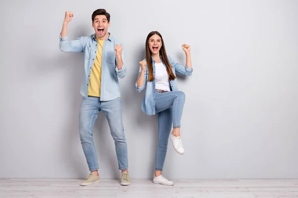 Foto da irmã sortuda irmão vestido camisas jeans levantando punhos vazio espaço isolado concreto cinza parede fundo — Fotografia de Stock