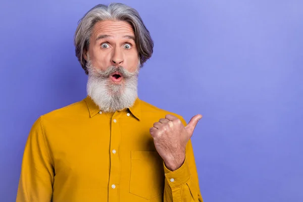 Foto av förvånad senior man indikerar finger tomt utrymme annons tyder på proposition isolerad över violett färg bakgrund — Stockfoto