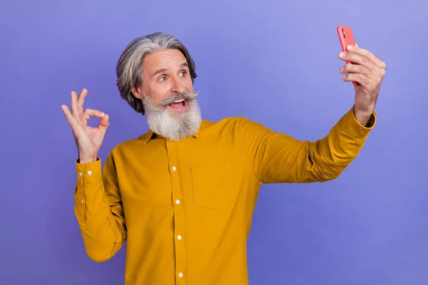 Foto van volwassen vrolijke man schieten selfie foto mobiele show okey symbool perfect ideaal geïsoleerd over paarse kleur achtergrond — Stockfoto