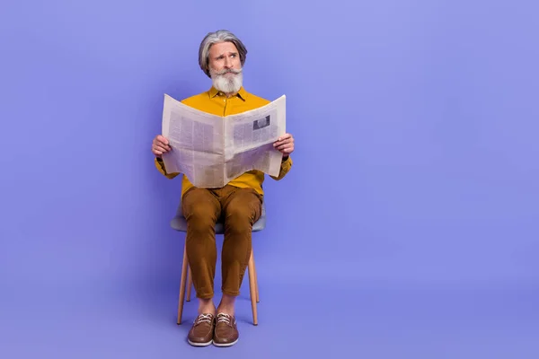 Retrato de atraente homem de cabelos grisalhos duvidosos lendo notícias espaço de cópia isolado sobre brilhante cor violeta roxo fundo — Fotografia de Stock