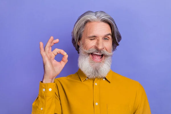 Foto de excitado alegre hombre maduro guiño ojo mostrar dedos okey símbolo anuncio perfecto decidir promo aislado sobre fondo de color púrpura — Foto de Stock
