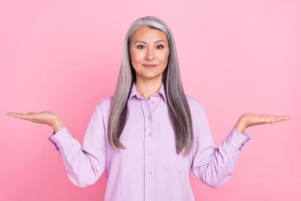 Portret van aantrekkelijke vrolijke zelfverzekerde grijs-harige vrouw vasthouden op palmen kopiëren ruimte ad geïsoleerd over roze pastel kleur achtergrond — Stockfoto