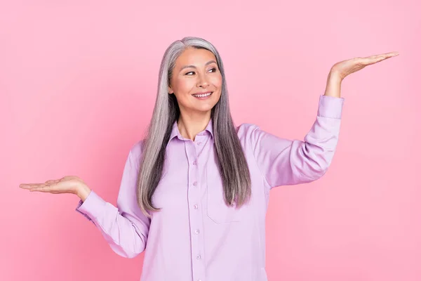 Portret van aantrekkelijke vrolijke zelfverzekerde grijs-harige vrouw houden kopieerruimte beslissen geïsoleerd over roze pastel kleur achtergrond — Stockfoto