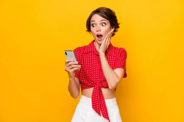 Foto van jong mooi verbaasd geschokt verrast meisje zie onverwacht nieuws in mobiele telefoon geïsoleerd op gele kleur achtergrond — Stockfoto