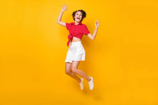 Foto de tamaño completo de la señora morena agradable impresionado salto usar camisa falda aislada sobre fondo de color amarillo — Foto de Stock