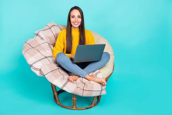 Potret orang yang cukup positif duduk kursi lembut menggunakan netbook nirkabel terisolasi pada warna latar belakang teal — Stok Foto