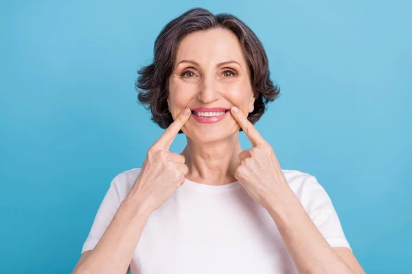 Фотопортрет женщина улыбается показывая пальцем, указывая на белые зубы виниры изолированные пастельно-синий цвет фона — стоковое фото