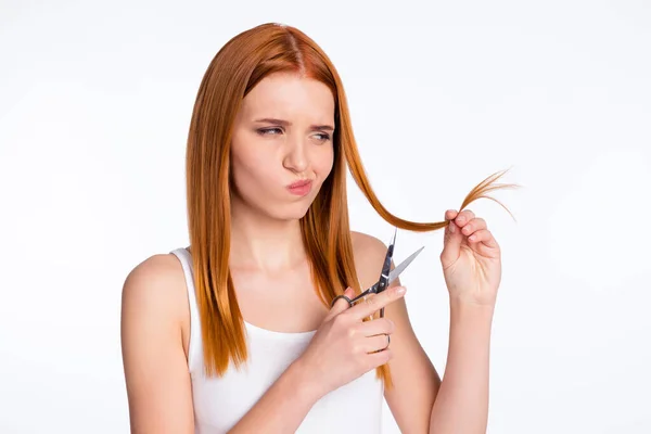 Foto de menina acho incerto hesite segurar tesoura pronta para cortar o cabelo isolado sobre fundo de cor cinza — Fotografia de Stock