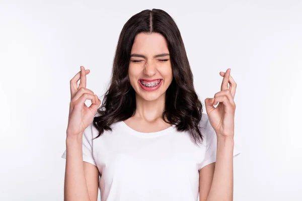Πορτρέτο της ελκυστική ονειρική ενθουσιασμένοι χαρούμενο κορίτσι φορώντας τιράντες προσεύχεται σταυρωμένα δάχτυλα απομονώνονται σε ανοιχτό γκρι χρώμα φόντο — Φωτογραφία Αρχείου