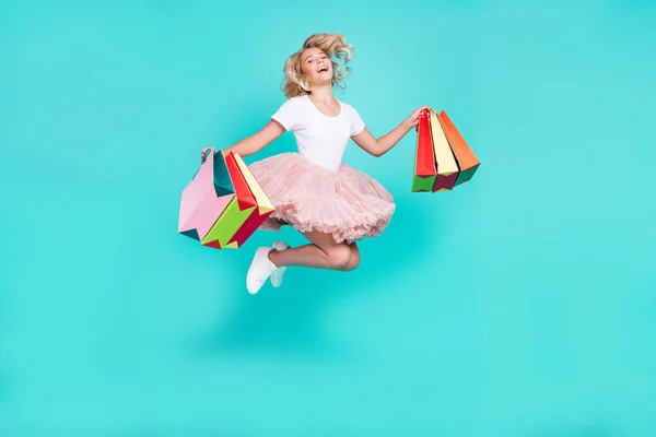 Photo of carefree active lady hold bargains jump wear white t-shirt skirt shoes isolated aquamarine color background — Stock Photo, Image