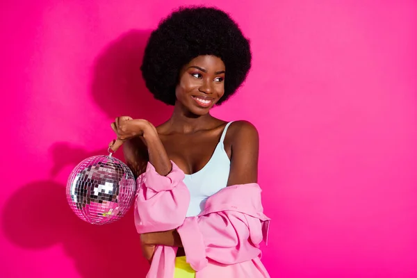 Fénykép imádnivaló édes sötét bőr hölgy viselni alkalmi ing gazdaság disco labda keres üres tér mosolygós elszigetelt rózsaszín háttér — Stock Fotó
