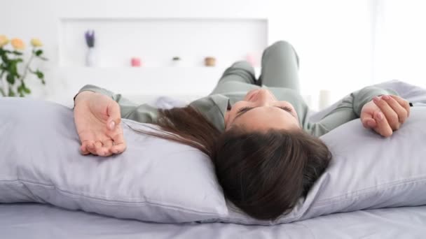 Señora despreocupada que pone la cama sedosa disfrutar de la siesta saludable abrazo almohada en habitación cómoda — Vídeo de stock