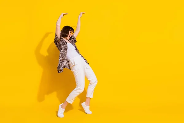 Foto de perfil em tamanho completo de senhora engraçada dança braço até desgaste óculos camisa calças sapatilhas isoladas no fundo cor amarela — Fotografia de Stock