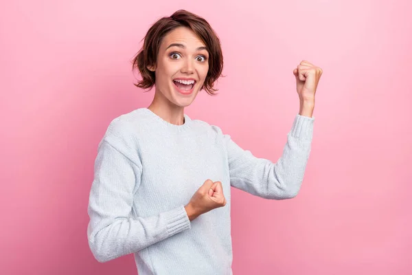 Foto de alegre feliz positiva bonita mujer joven levantar puños ganador celebrar aislado en el fondo de color rosa —  Fotos de Stock