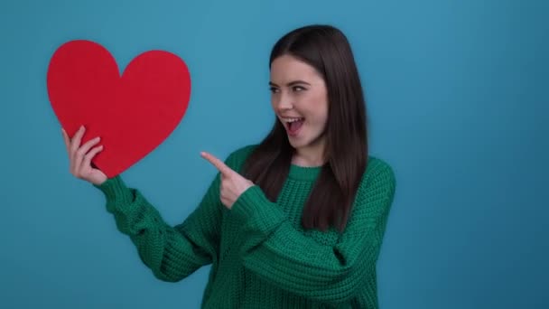 Wanita bergaya menunjukkan kepalan jantung lotere terisolasi warna biru latar belakang — Stok Video