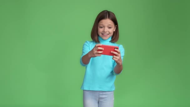 Adicto niño jugar dispositivo velocidad carrera puño arriba ganar aislado color verde fondo — Vídeos de Stock