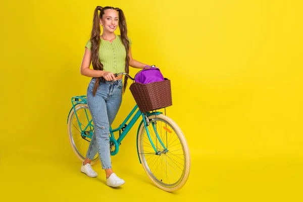 Tamanho do corpo de comprimento total vista de menina alegre atraente andando de bicicleta passando férias isoladas sobre fundo de cor amarelo brilhante — Fotografia de Stock