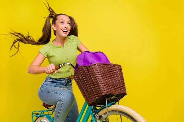 Retrato de menina atraente engraçado alegre menina andar de bicicleta se divertindo isolado sobre fundo de cor amarela brilhante — Fotografia de Stock