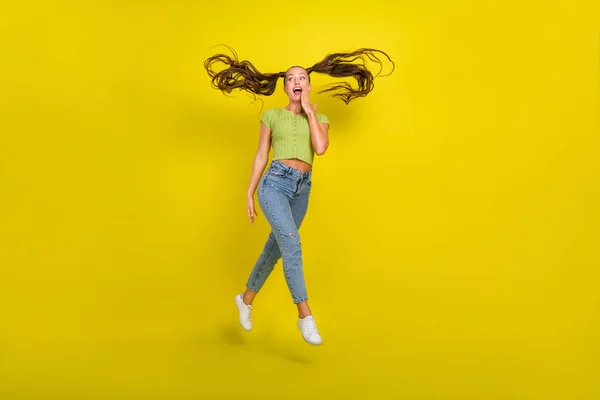 Повнометражний вигляд на тіло красивої дівчини вражений веселою дівчиною, що стрибає, розважаючись ізольовано на яскраво-жовтому кольоровому фоні — стокове фото
