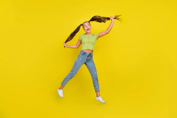 Foto de comprimento total de impressionado millennial morena senhora salto olhar espaço vazio desgaste jeans t-shirt sapatos isolados no fundo amarelo — Fotografia de Stock