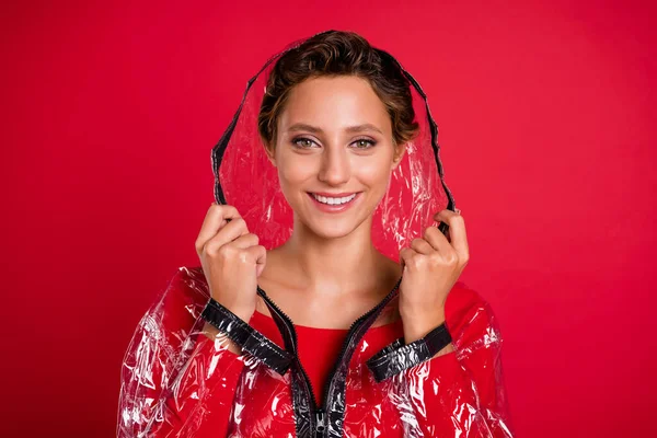 Foto de adorável doce jovem senhora usar capa capa de chuva sorrindo isolado fundo de cor vermelha — Fotografia de Stock