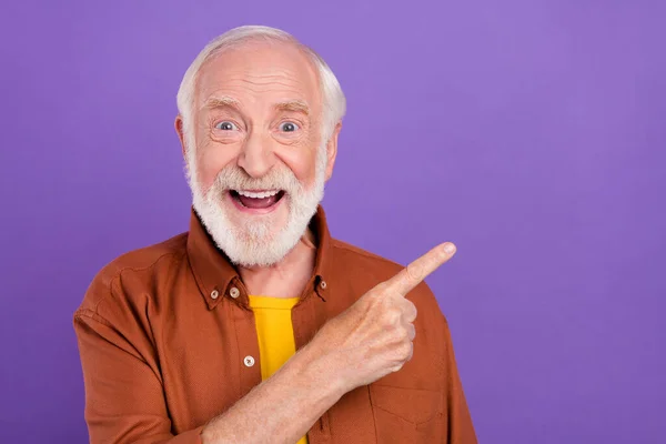 Foto de hooray anciano hombre punto espacio vacío con camisa marrón aislado sobre fondo de color violeta vivo — Foto de Stock