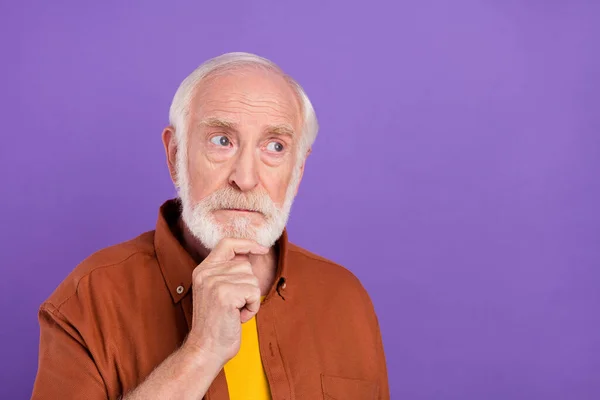 Foto de hombre viejo estricto mirada espacio vacío usando camisa marrón aislado sobre fondo de color violeta vivo —  Fotos de Stock