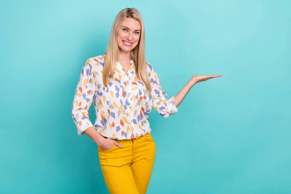 Photo of funny millennial blond lady hold empty space wear printed blouse pants isolated on teal color background — Stock Photo, Image