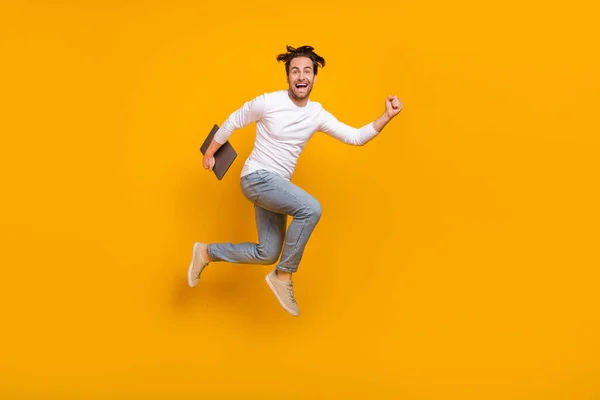 Foto von hurra brunet millennial guy run mit laptop tragen shirt jeans turnschuhe isoliert auf gelbem hintergrund — Stockfoto