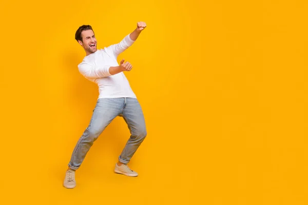 Full length photo of impressed brunet millennial guy drive wear shirt jeans footwear isolated on yellow background — Stock Photo, Image