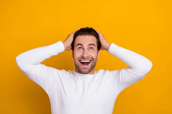 Foto de los brazos del hombre asombrado positivo en la cabeza mira interesado por encima del espacio vacío aislado en el fondo de color amarillo —  Fotos de Stock