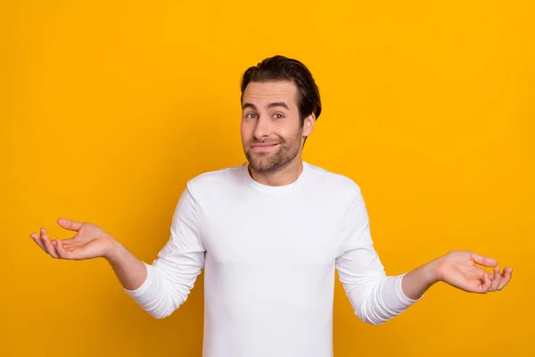 Photo of millennial unsure brunet guy shrug shoulders wear white shirt isolated on bright yellow color background — 图库照片