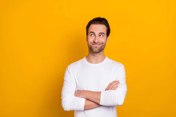 Retrato de tipo positivo pacífico cruzó las manos mira interesado espacio vacío aislado sobre fondo de color amarillo — Foto de Stock