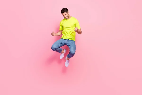 Full length photo of hooray brunet hairdo young guy jump yell wear green t-shirt jeans isolated on pink color background — Stock Photo, Image