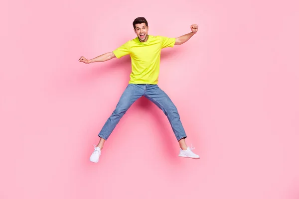 Foto em tamanho completo de impressionado morena penteado millennial cara saltar gritar desgaste verde t-shirt jeans isolado no fundo cor-de-rosa — Fotografia de Stock