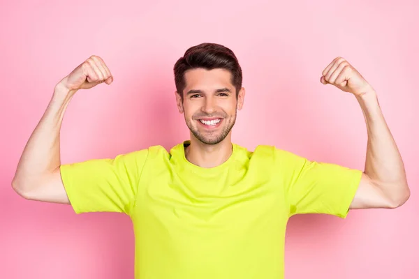 Portrait of attractive cheerful guy demonstrating powerful muscles isolated over pink pastel color background — 图库照片