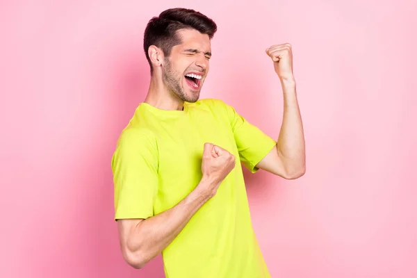 Foto retrato alegre morena hombre usando brillante camiseta llena de alegría gesto como ganador aislado pastel rosa color fondo —  Fotos de Stock