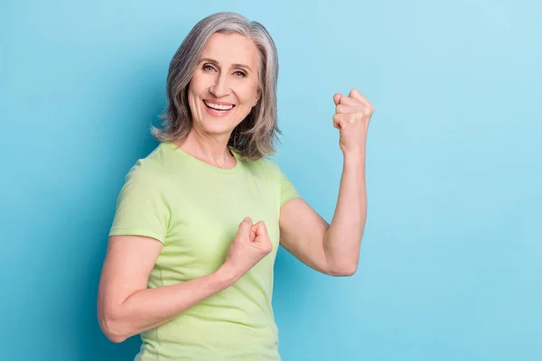 Photo portret starsza kobieta zainteresowana uśmiechem gestykulując jak zwycięzca odizolowany pastelowy niebieski kolor tła — Zdjęcie stockowe