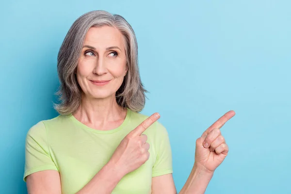 Photo portrait elder woman curious interested smiling pointing blank space isolated pastel blue color background — 图库照片