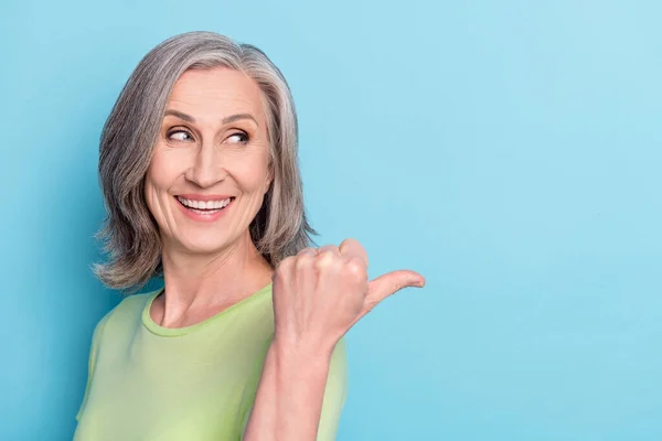 Φωτογραφία από γοητευτικό ευτυχισμένη ηλικιωμένη γυναίκα ματιά σημείο δάχτυλο κενό χώρο επιλέξτε απομονωμένο σε μπλε φόντο χρώμα — Φωτογραφία Αρχείου