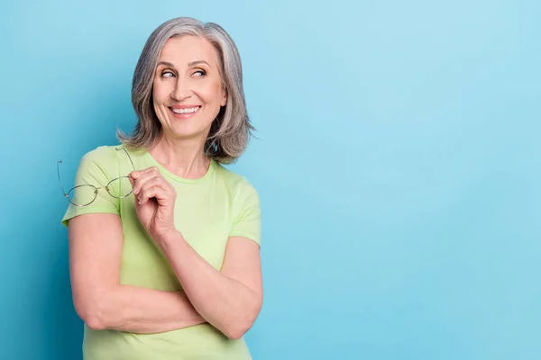 Foto van dromerig gelukkig mooi oud vrouw blik leeg ruimte houd handen glazen geïsoleerd op blauwe kleur achtergrond — Stockfoto