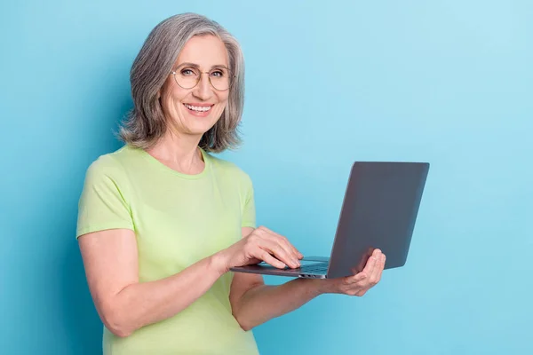 Photo de jolie jolie mignonne vieille femme sourire bonne humeur tenir les mains ordinateur isolé sur fond de couleur bleue — Photo