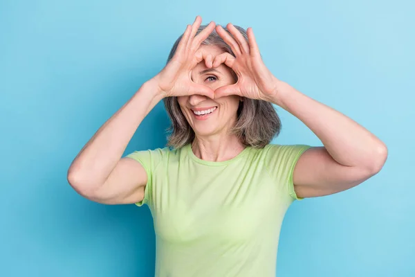 Foto von attraktiven glücklich schöne alte Frau machen Finger Herzform aussehen Augenblick isoliert auf blauem Hintergrund — Stockfoto