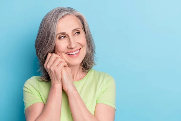 Foto de atraente sonhador velha mulher segurar punhos rosto bom humor olhar espaço vazio isolado no fundo cor azul pastel — Fotografia de Stock