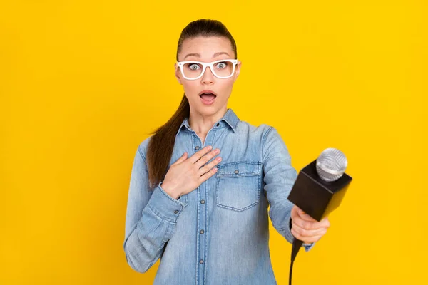 Foto de excitada mujer joven funky desgaste vaquero camisa gafas brazo pecho tacking entrevista aislado color amarillo fondo — Foto de Stock