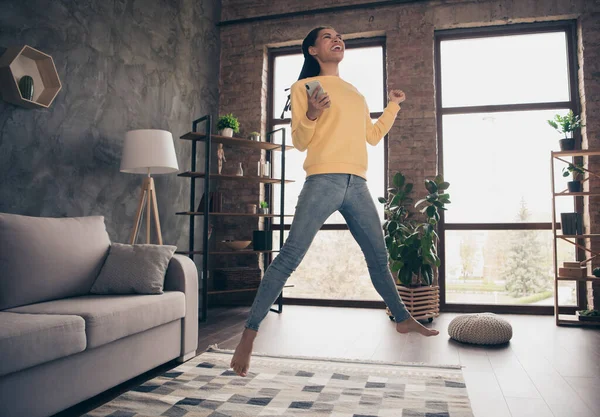 Foto van gelukkige grappige jonge dame dragen gele trui rijzende vuist houden moderne gadget springen binnen kamer huis — Stockfoto
