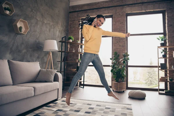 Volledige lengte foto van vrolijke gekke vrolijke afro-Amerikaanse vrouw springen win talk telefoon binnen in huis — Stockfoto