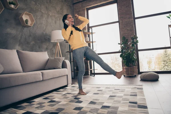 Foto van leuke gelukkige jonge dame dragen gele trui rijzende vuist praten moderne gadget binnen kamer thuis — Stockfoto